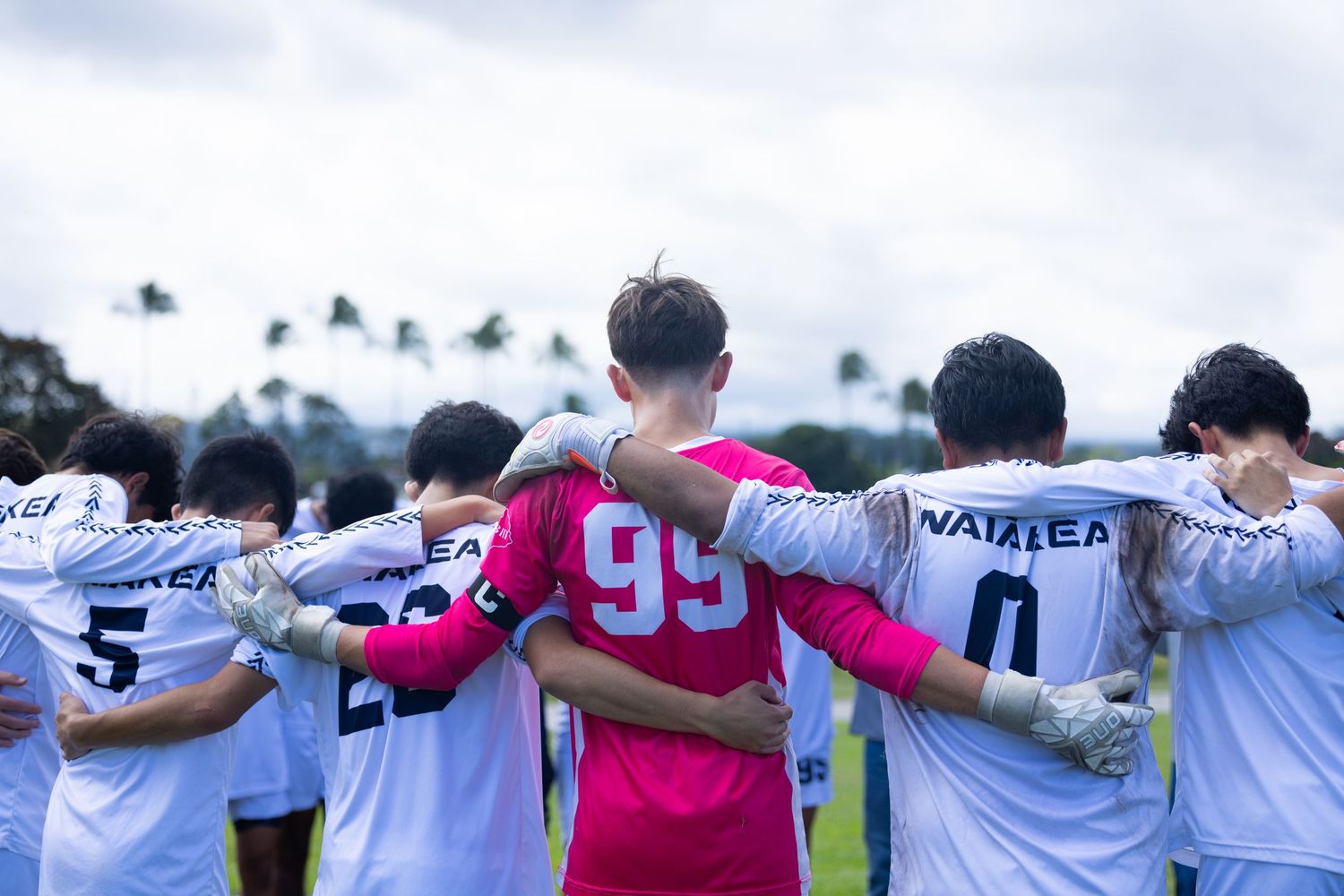 Team members standing with arms around each other's shoulders in unity formation.
