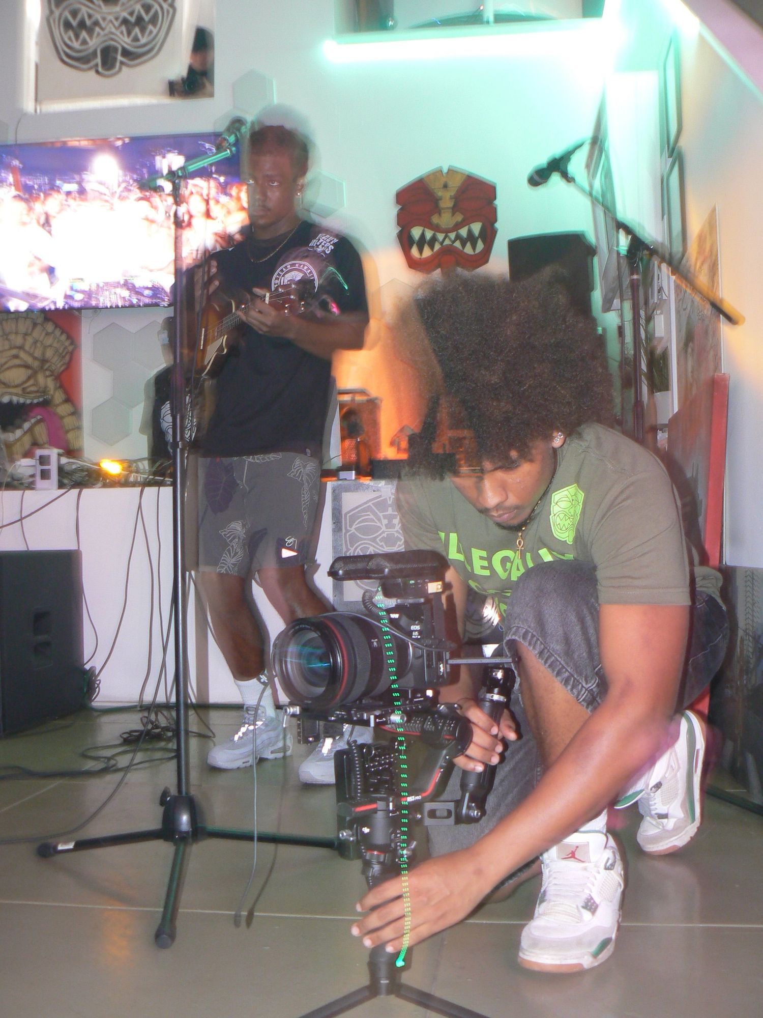 Musicians rehearsing in a studio space with teal-colored lighting and equipment.