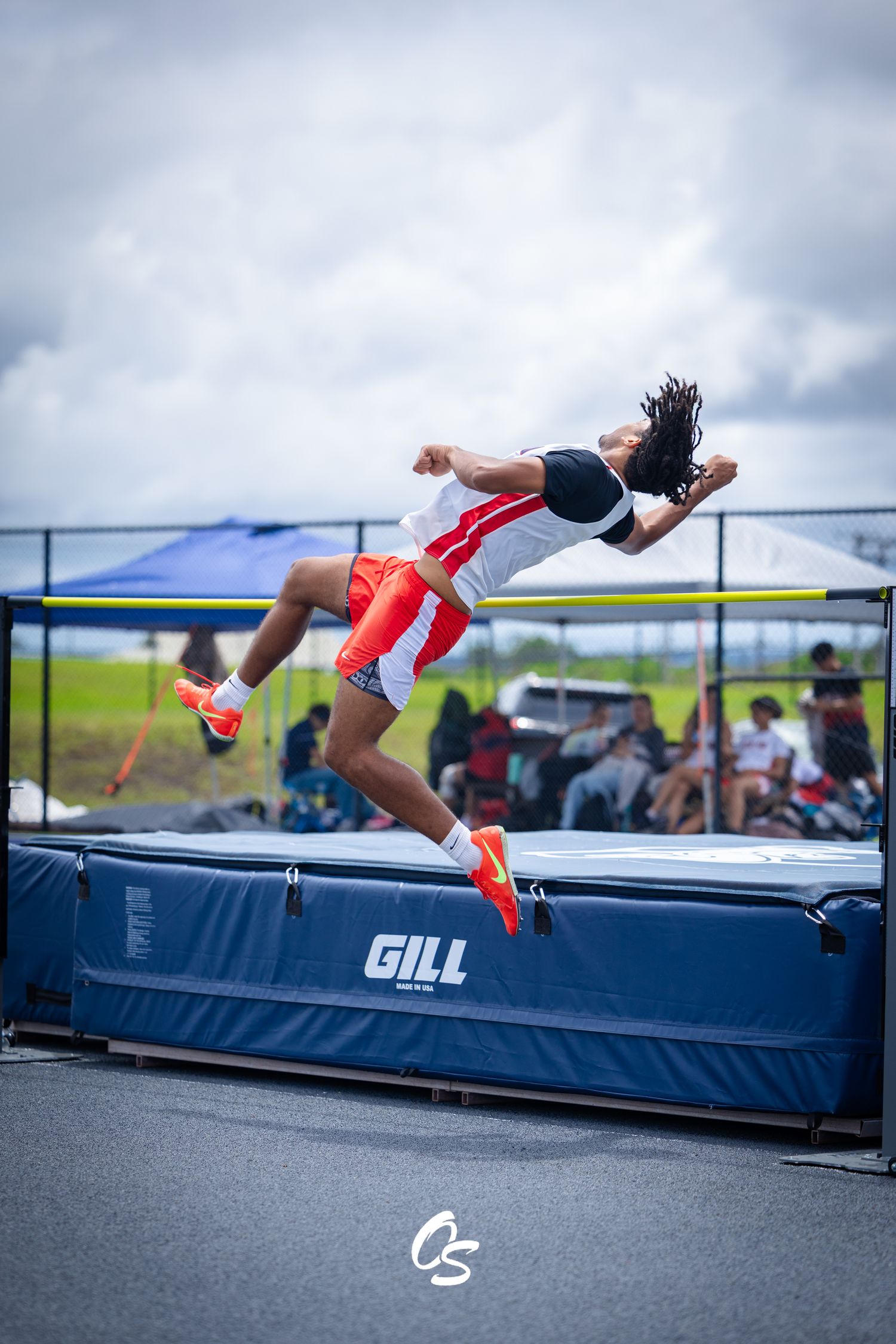 High jump athlete performing Fosbury Flop technique over bar during track and field competition.
