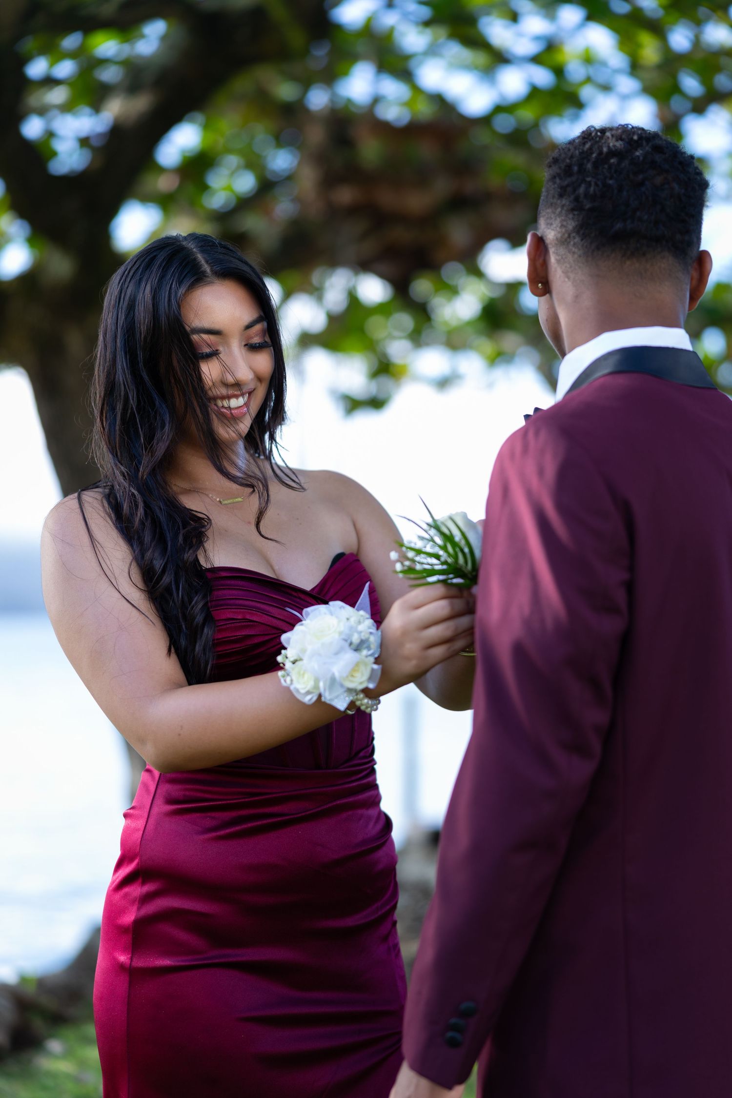Couple in burgundy formal wear sharing a moment during outdoor photo session.