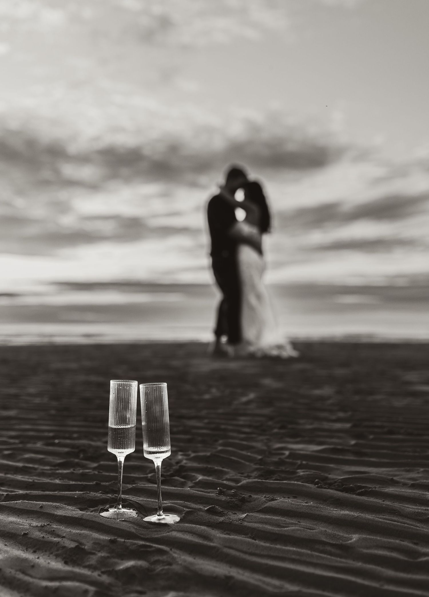 black and white image of couple out of focus and champagne glasses to celebrate