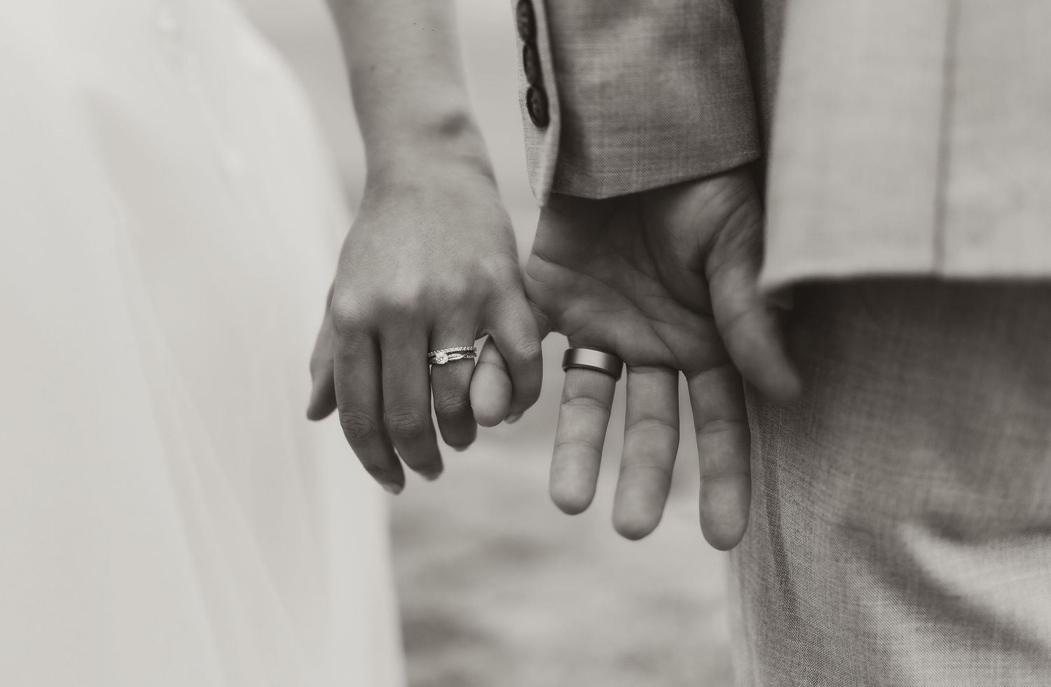 black and white image of bride and groom holding hands