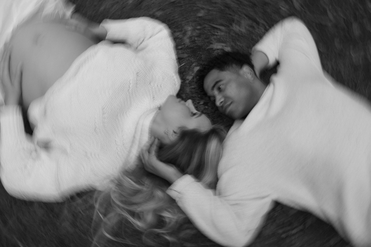 Couple lying together on the grass in a black and white portrait