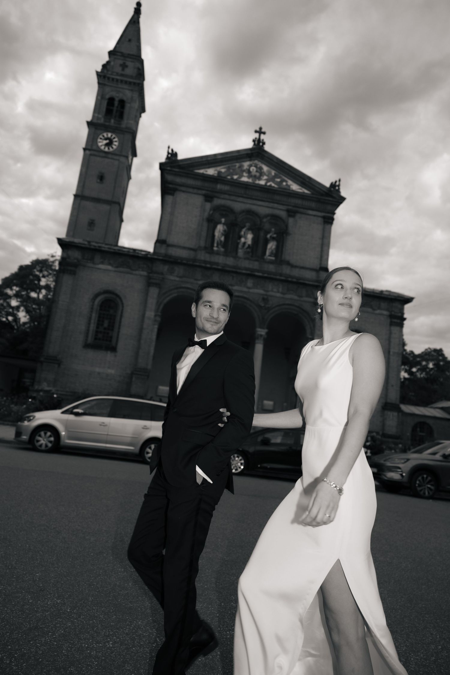 Newlyweds crossing the street in front of a church in black and white