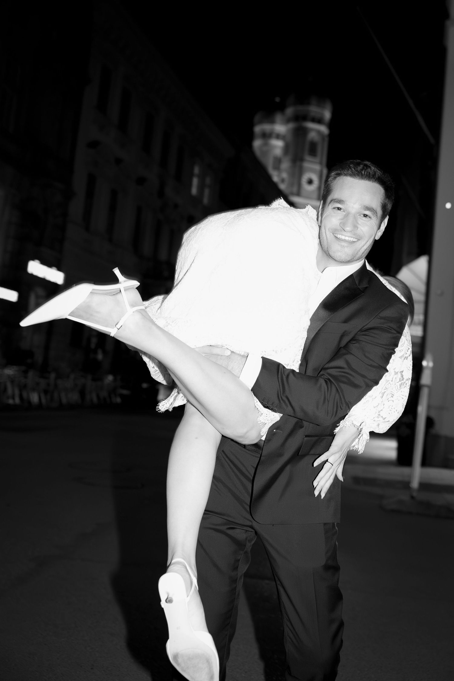 Groom carrying his bride through the city at night