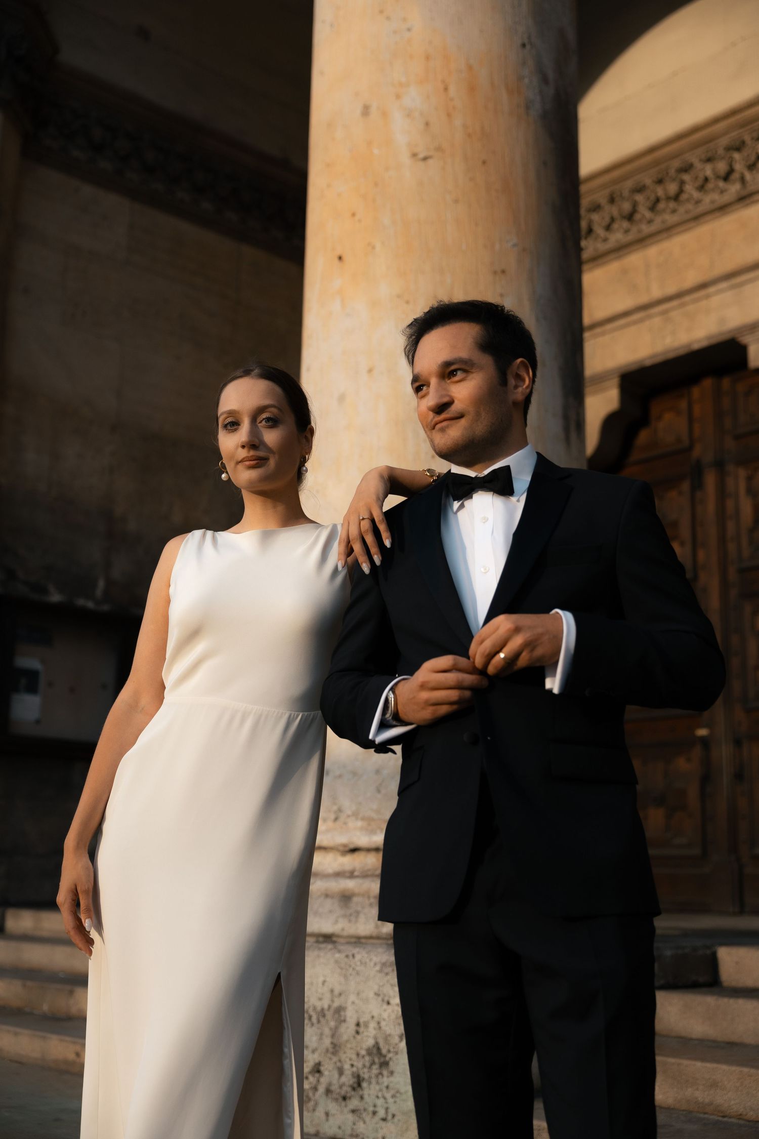 Newlyweds standing beneath a grand stone column