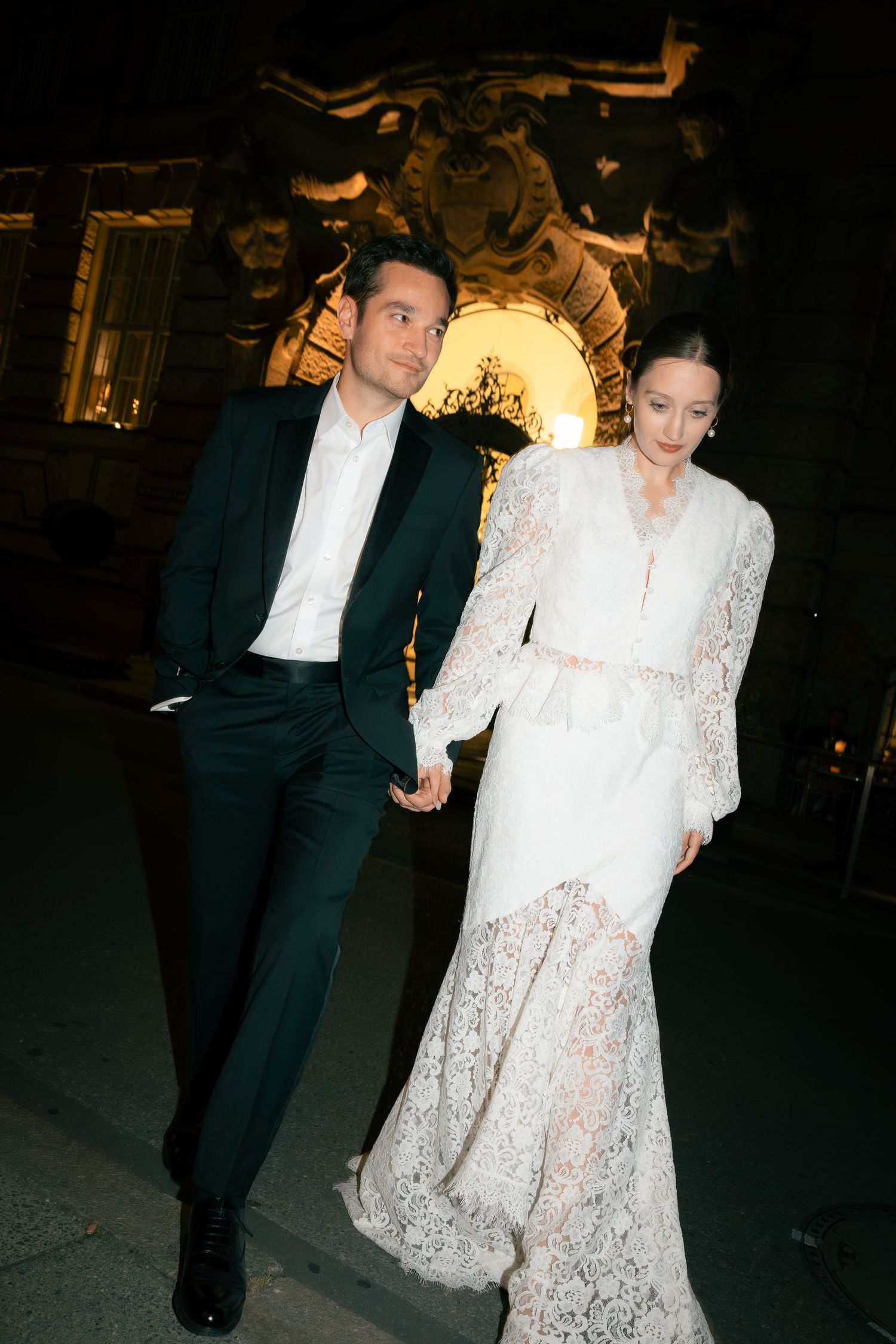 Newlywed couple crossing the street at night hand in hand