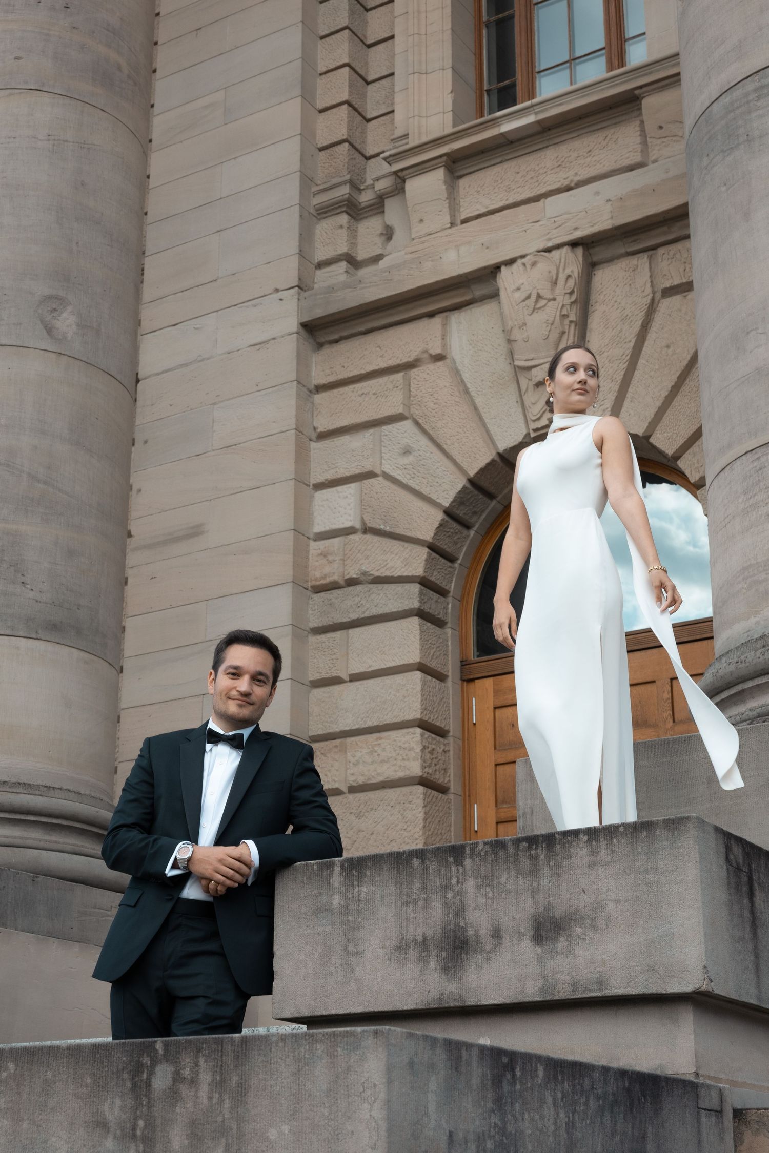 Newlyweds standing on stairs in front of a historical building
