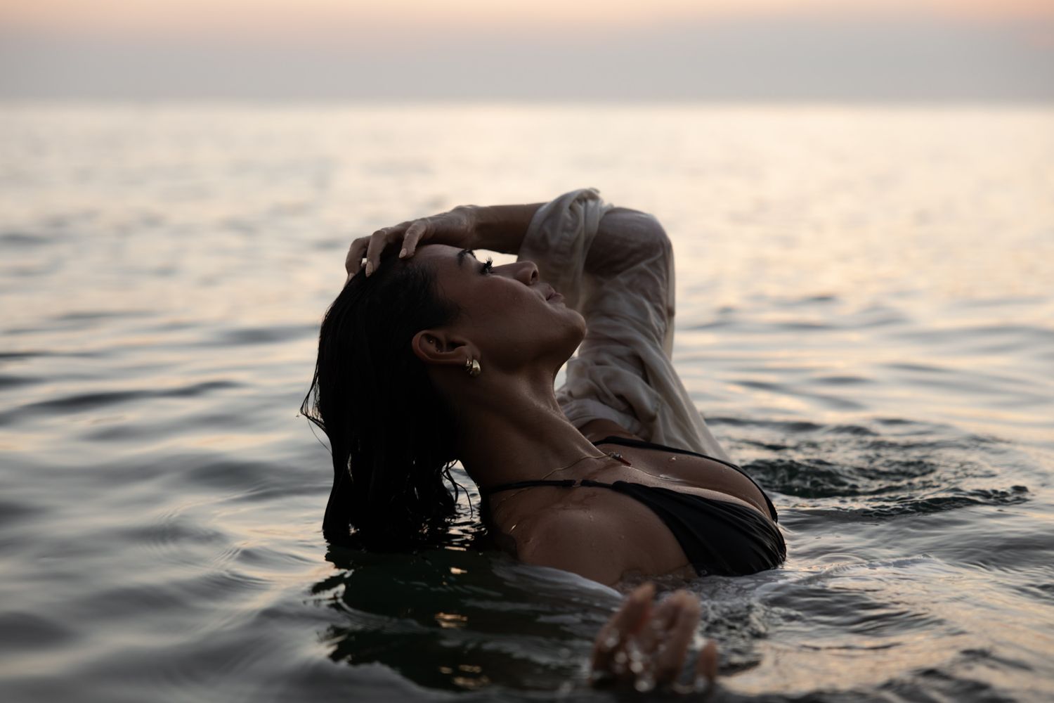Woman floating in the water at sunset