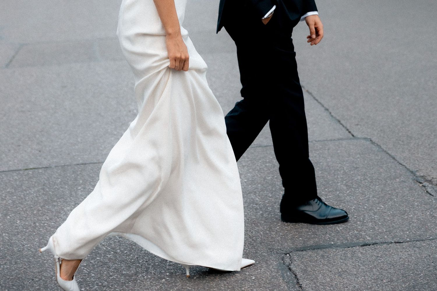 Bride and groom walking together in a cropped editorial photograph