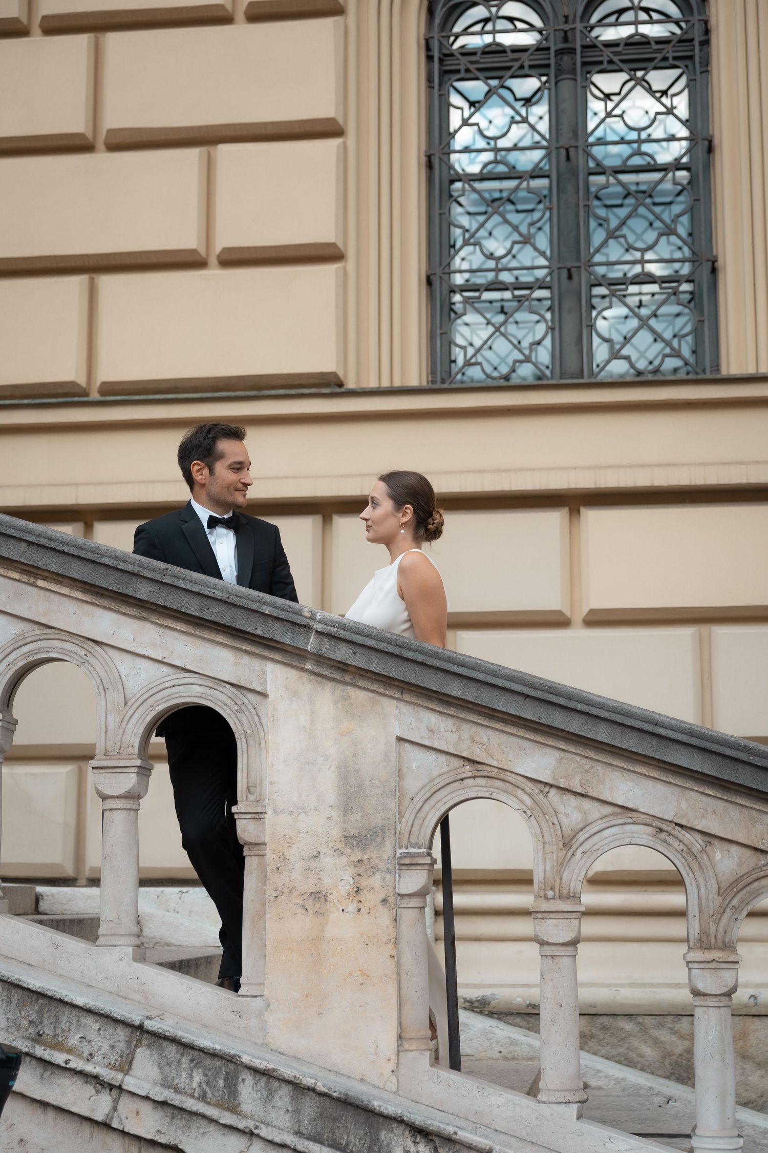 Newlyweds standing on stairs in front of a historical building