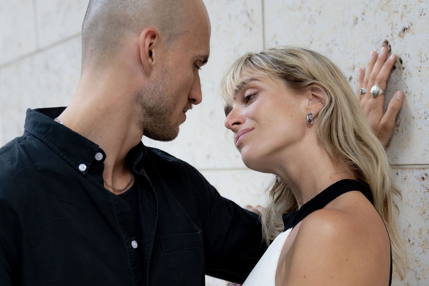 Couple sharing an intimate moment against a stone wall