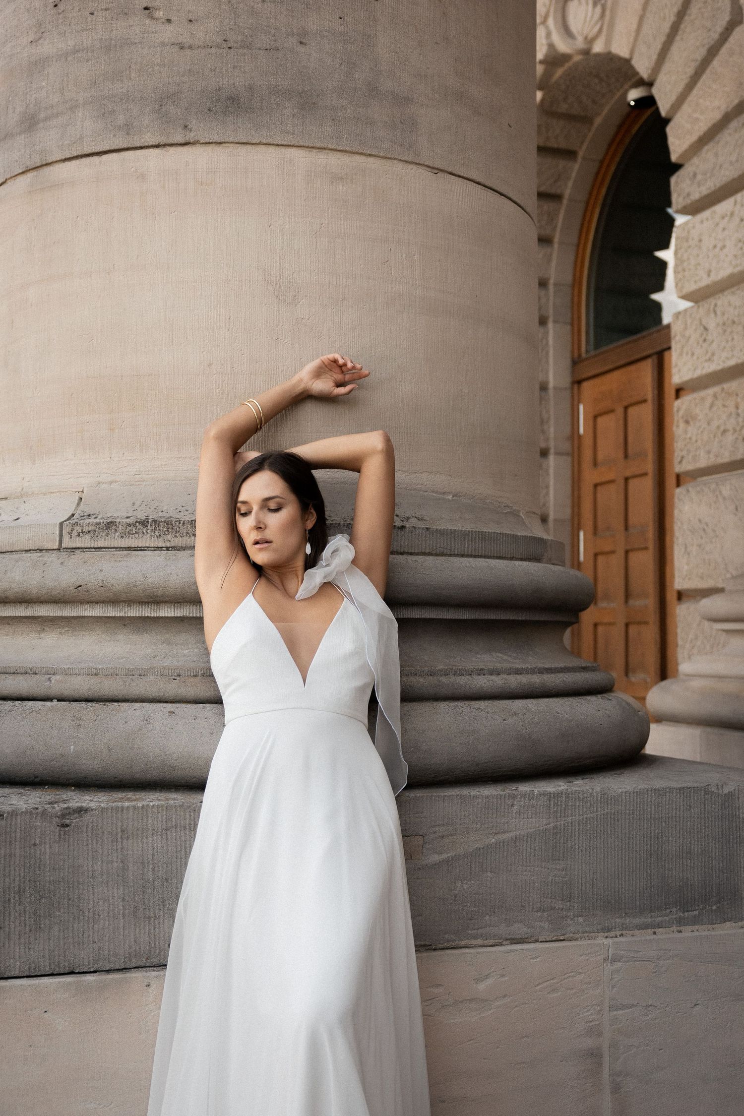 Bride posing against a monumental stone column