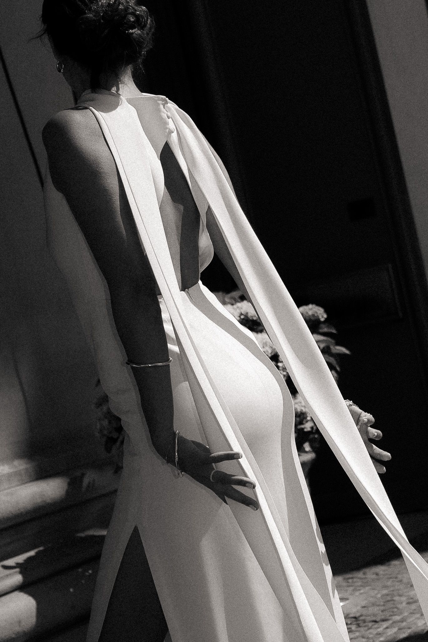 Bride photographed from behind showing the flowing back of her wedding dress in black and white