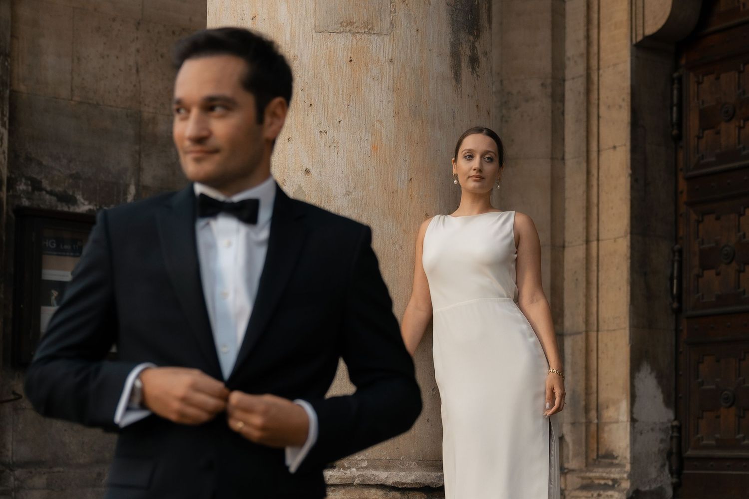 Newlyweds standing beneath a grand stone column