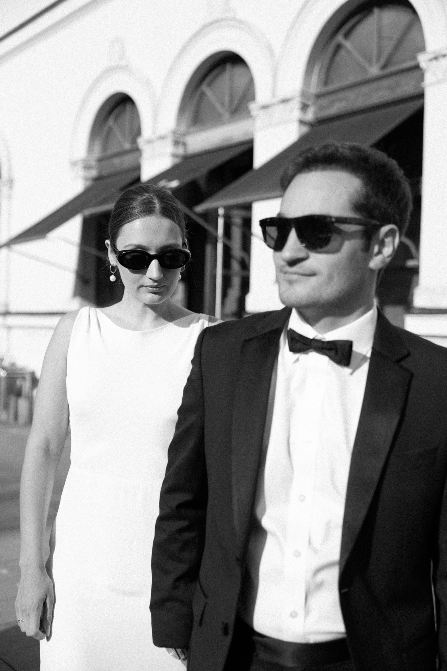 Newlyweds walking through the city wearing sunglasses