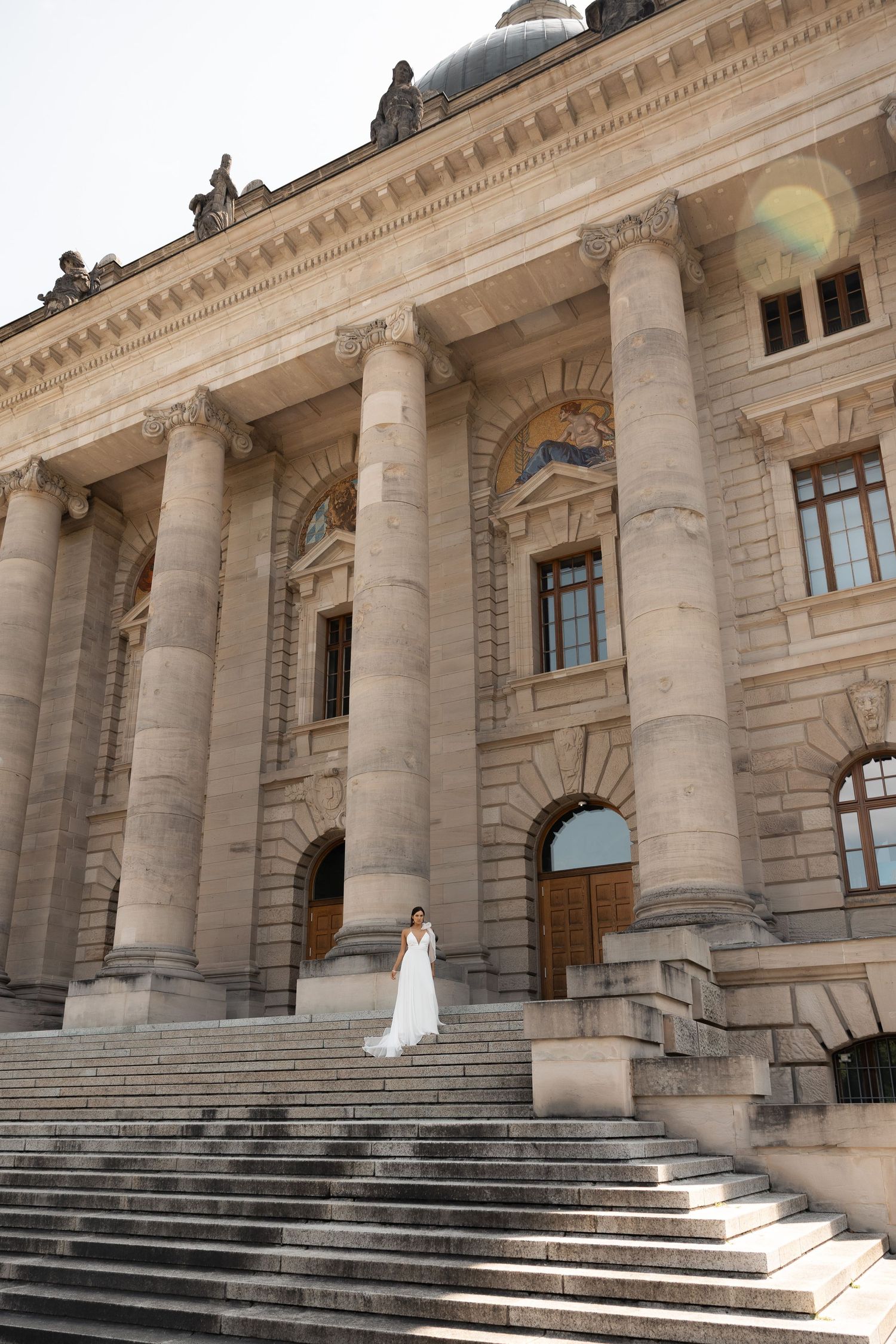 Bride standing alone on the steps of a grand historic building
