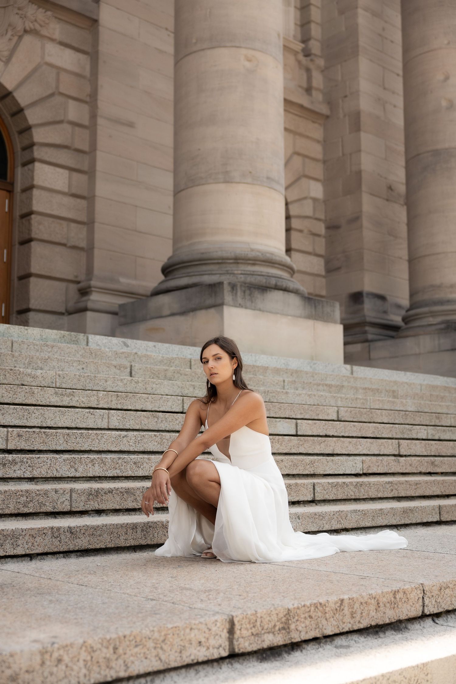 Bride posing alone on stairs in front of a historic building