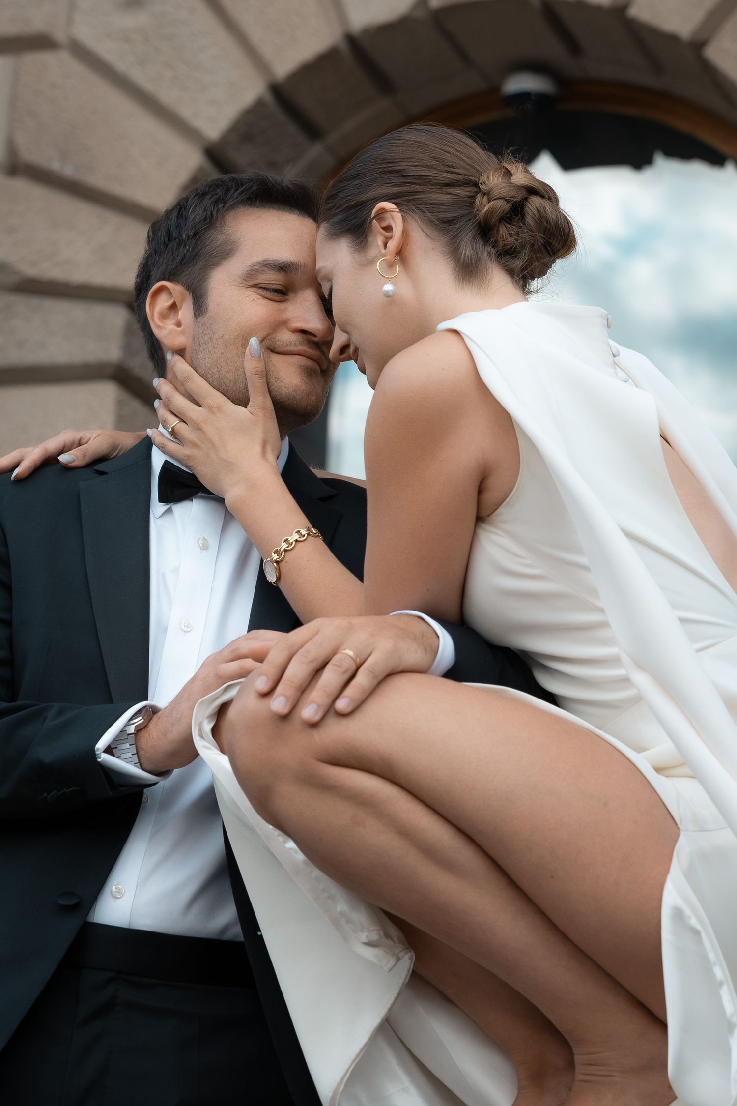 Newlywed couple sitting closely together outside a historic building