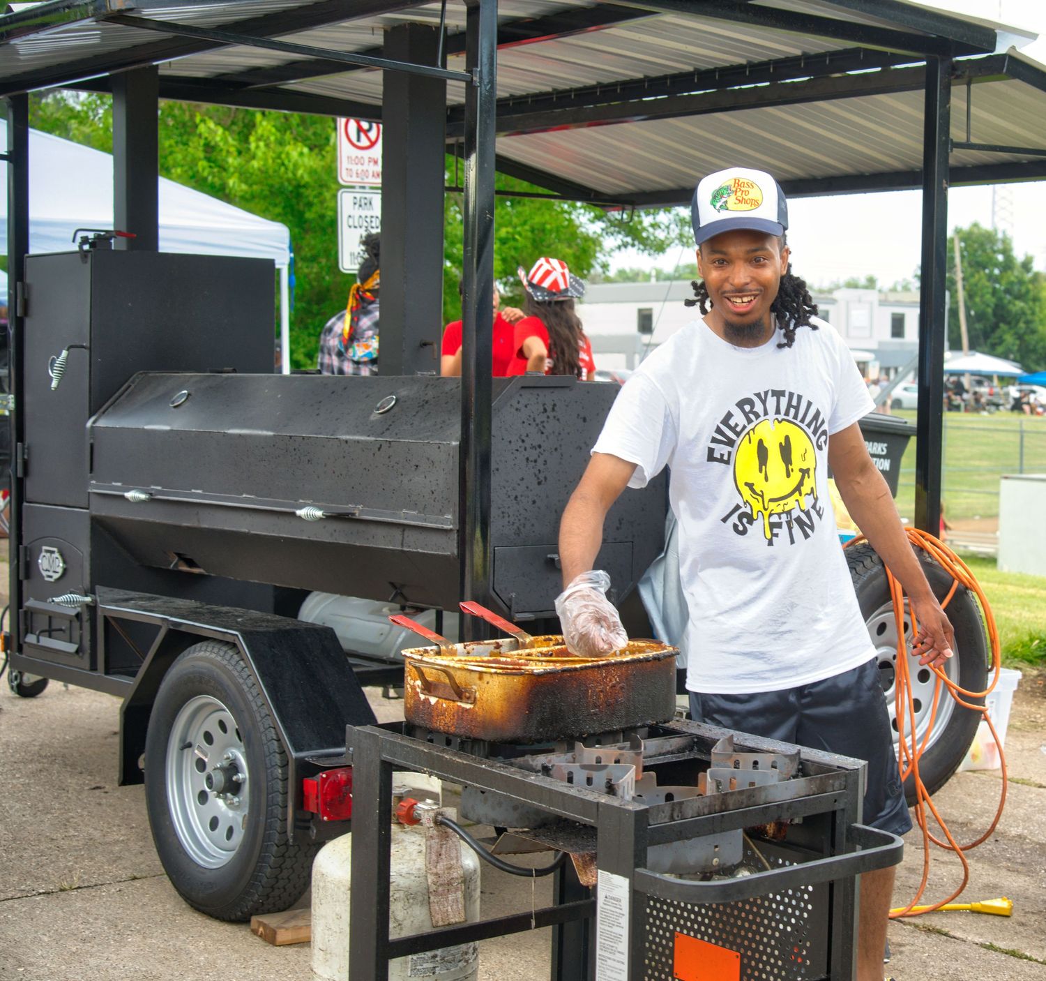 A man is grilling food on a trailer at an outdoor event.