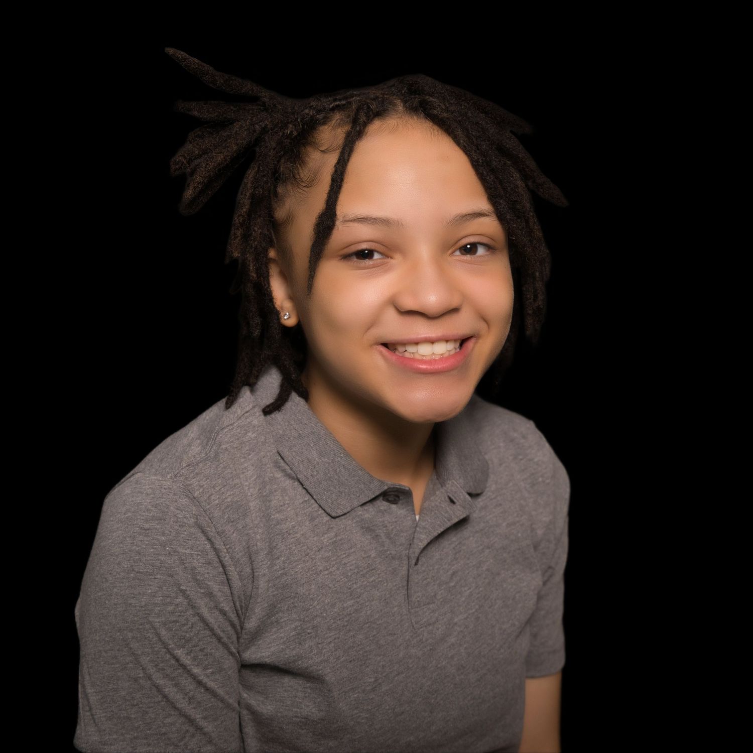 A smiling woman with short dark hair is wearing a white shirt against a black background.