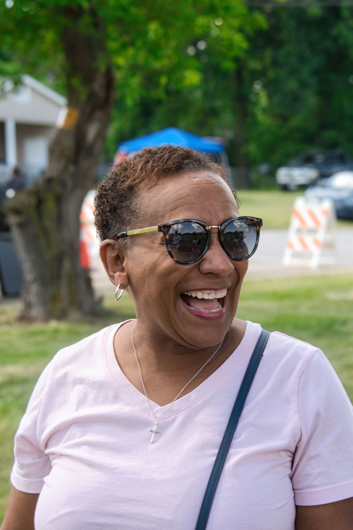 An older woman with sunglasses is smiling and looking at the camera.