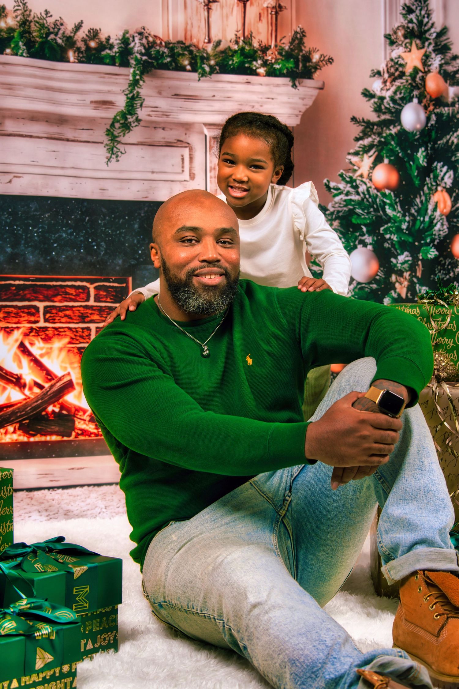 A smiling older woman in a red shirt is sitting in front of a fireplace with Christmas decorations.