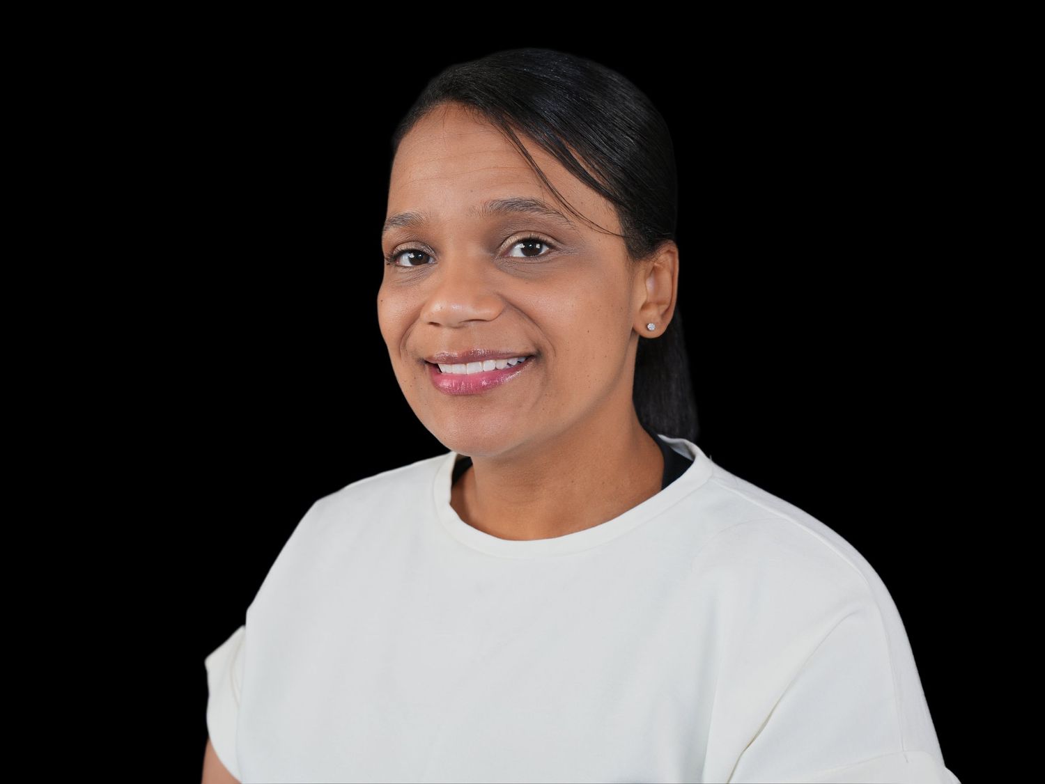 A young woman with dreadlocks is smiling and wearing a gray shirt.