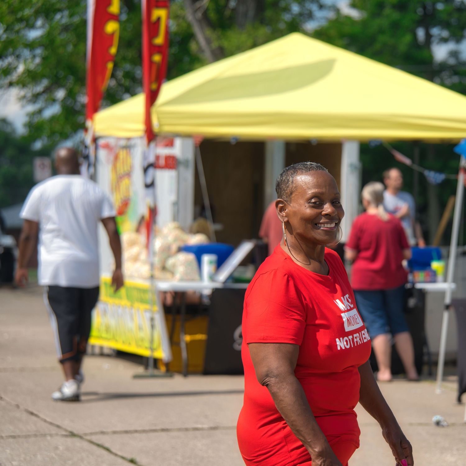A woman in a red shirt is standing and smiling at the camera.