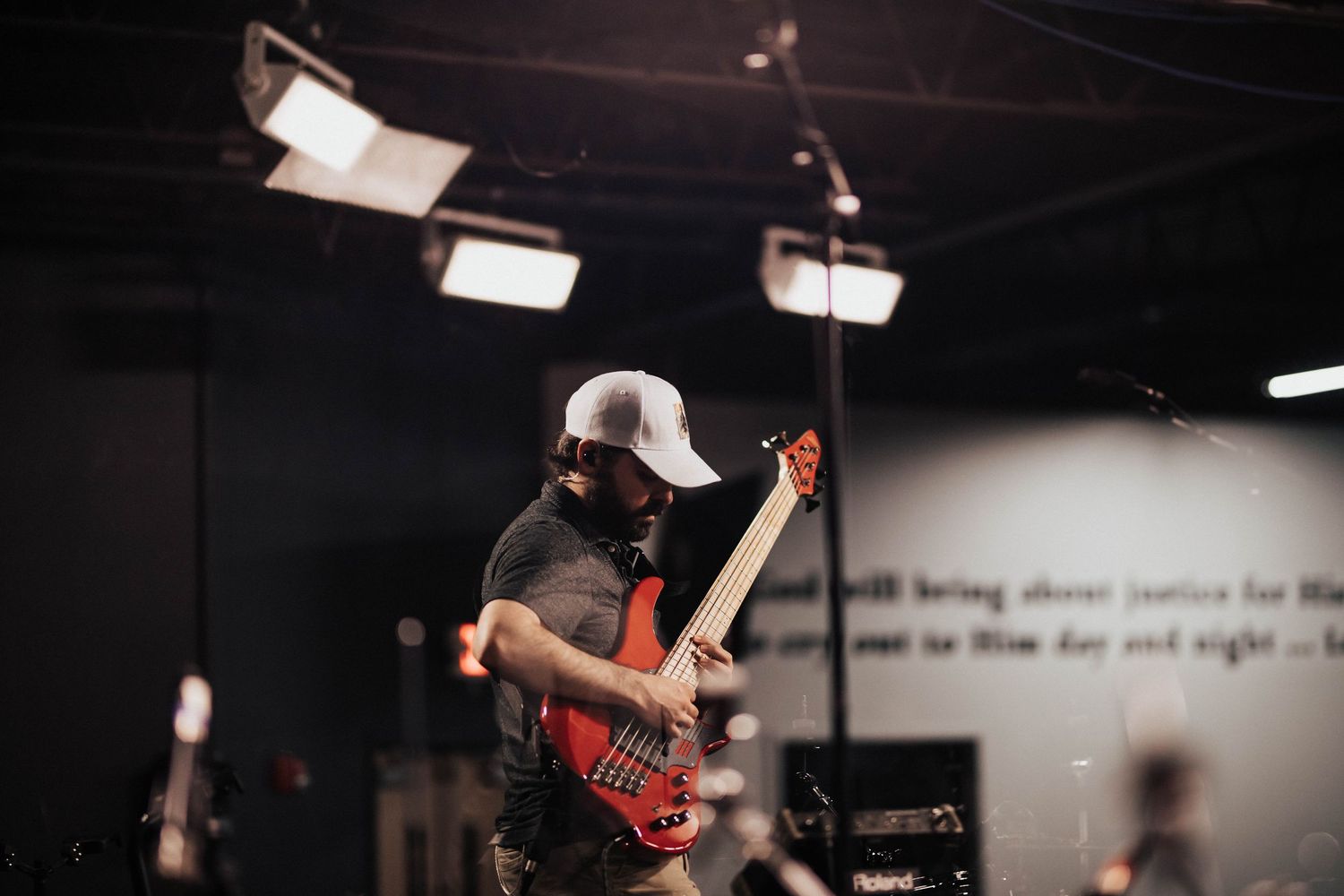 Musician plays red bass guitar under stage lights during church worship performance.