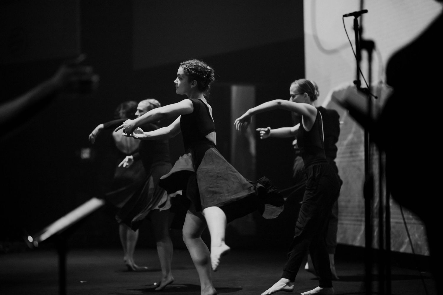 Black and white photo of female dancers performing contemporary dance on a dark stage.