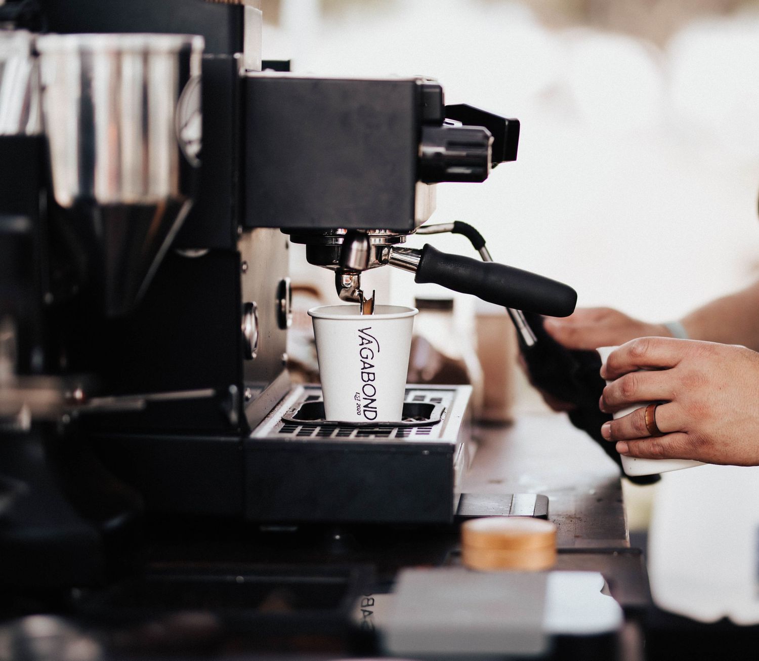 Barista uses espresso machine to prepare Vagabond Coffee in a white cup.