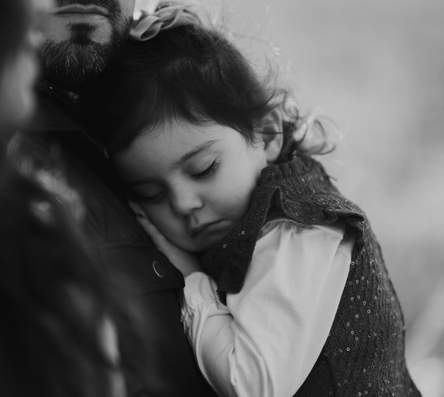 Black and white portrait of a young girl resting her head on someone's shoulder.