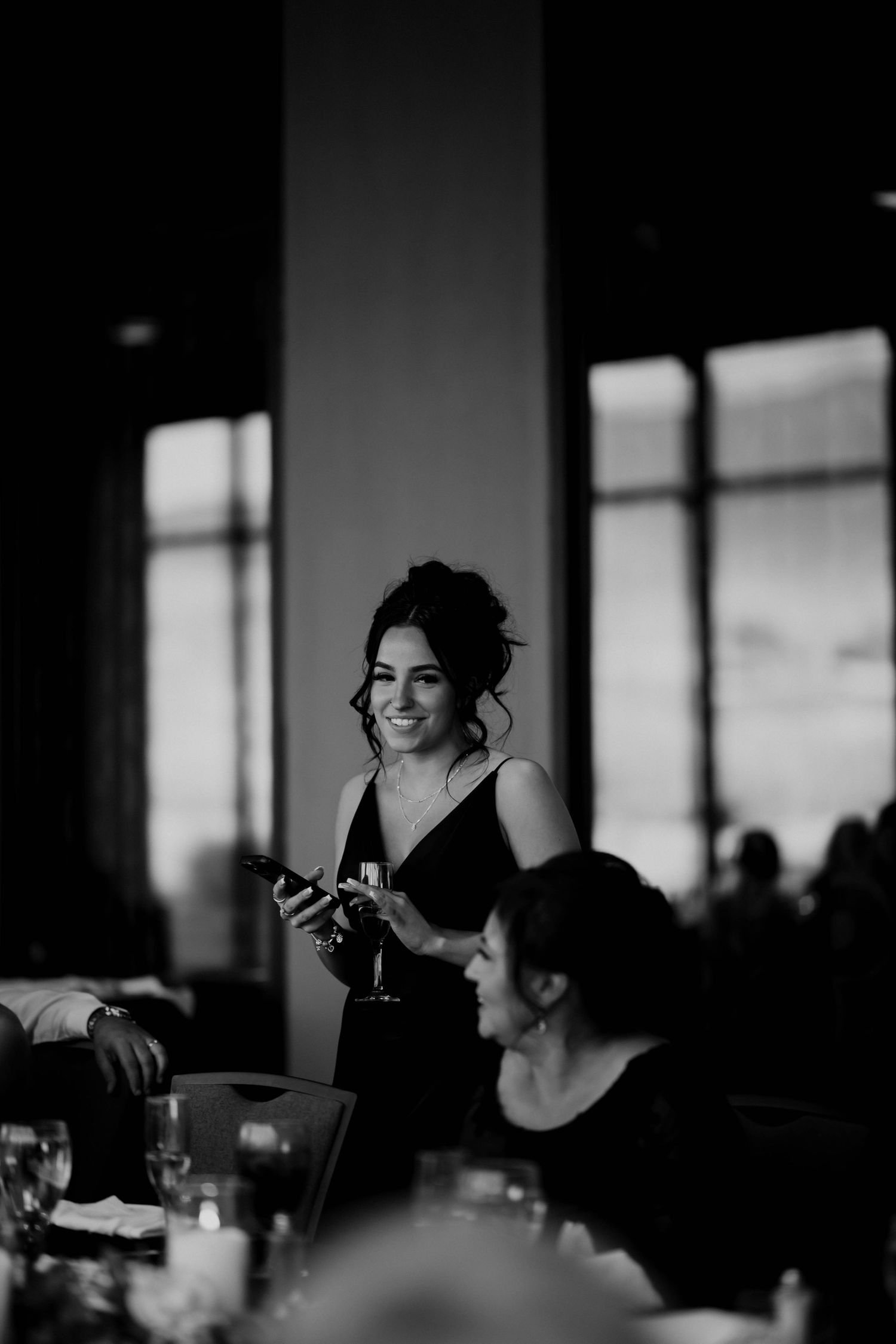 Bridesmaid smiling and giving a toast speech at an elegant wedding reception dinner.