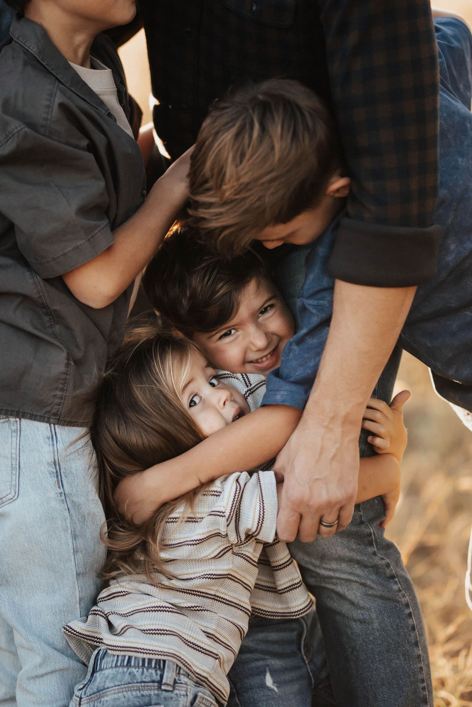 Two young children hugging and laughing together during an outdoor family photo session.
