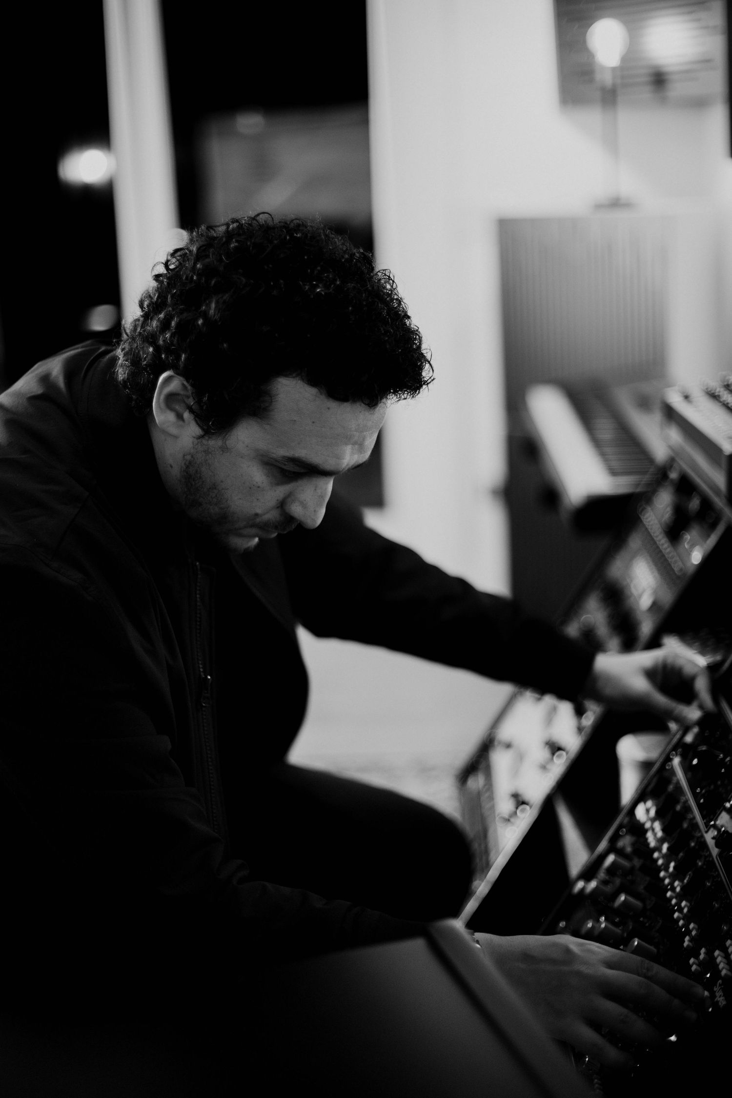 Black and white photo of a music producer working at a professional recording studio mixing console.