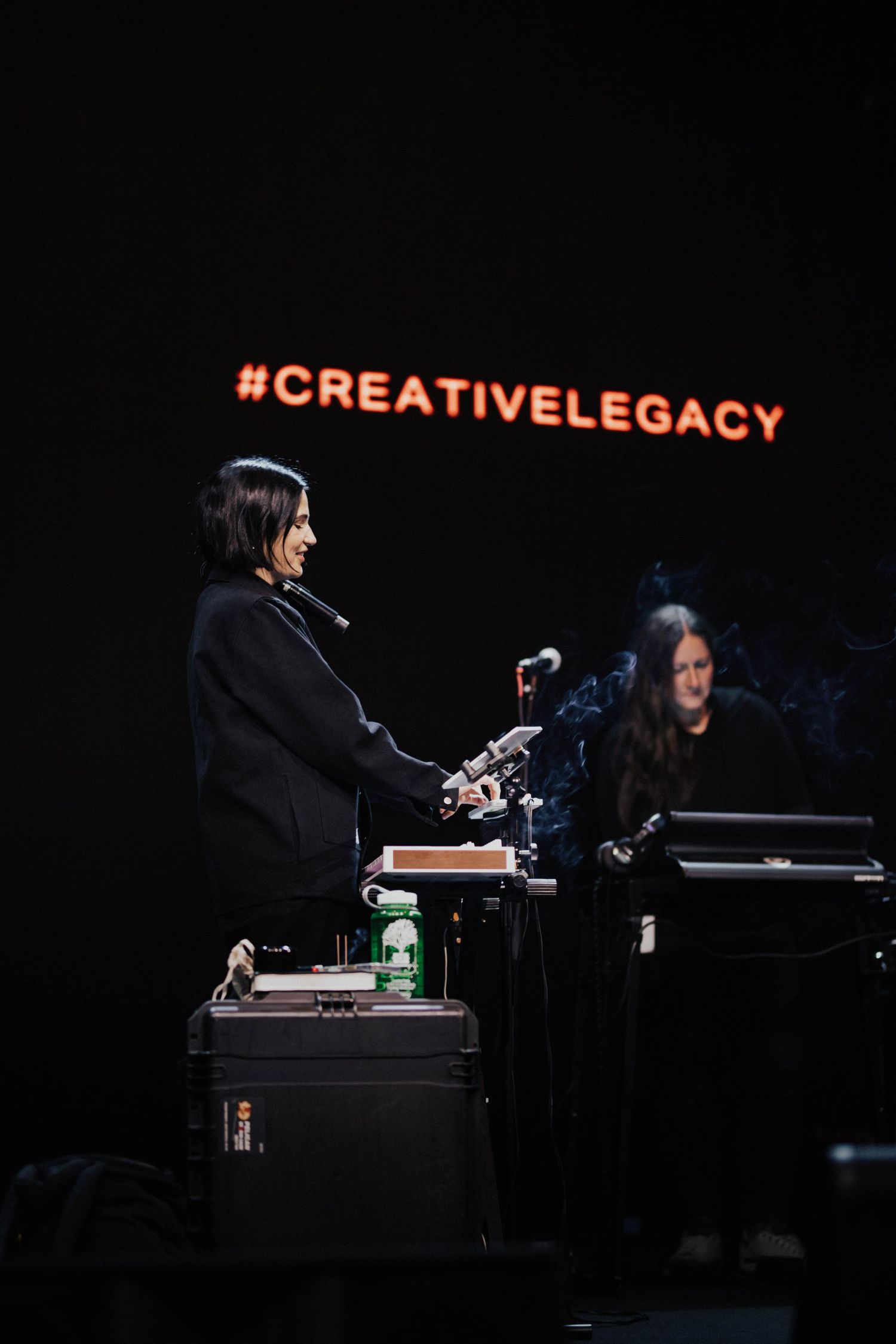 Female musician performing on stage at a Creative Legacy event with equipment and backdrop.