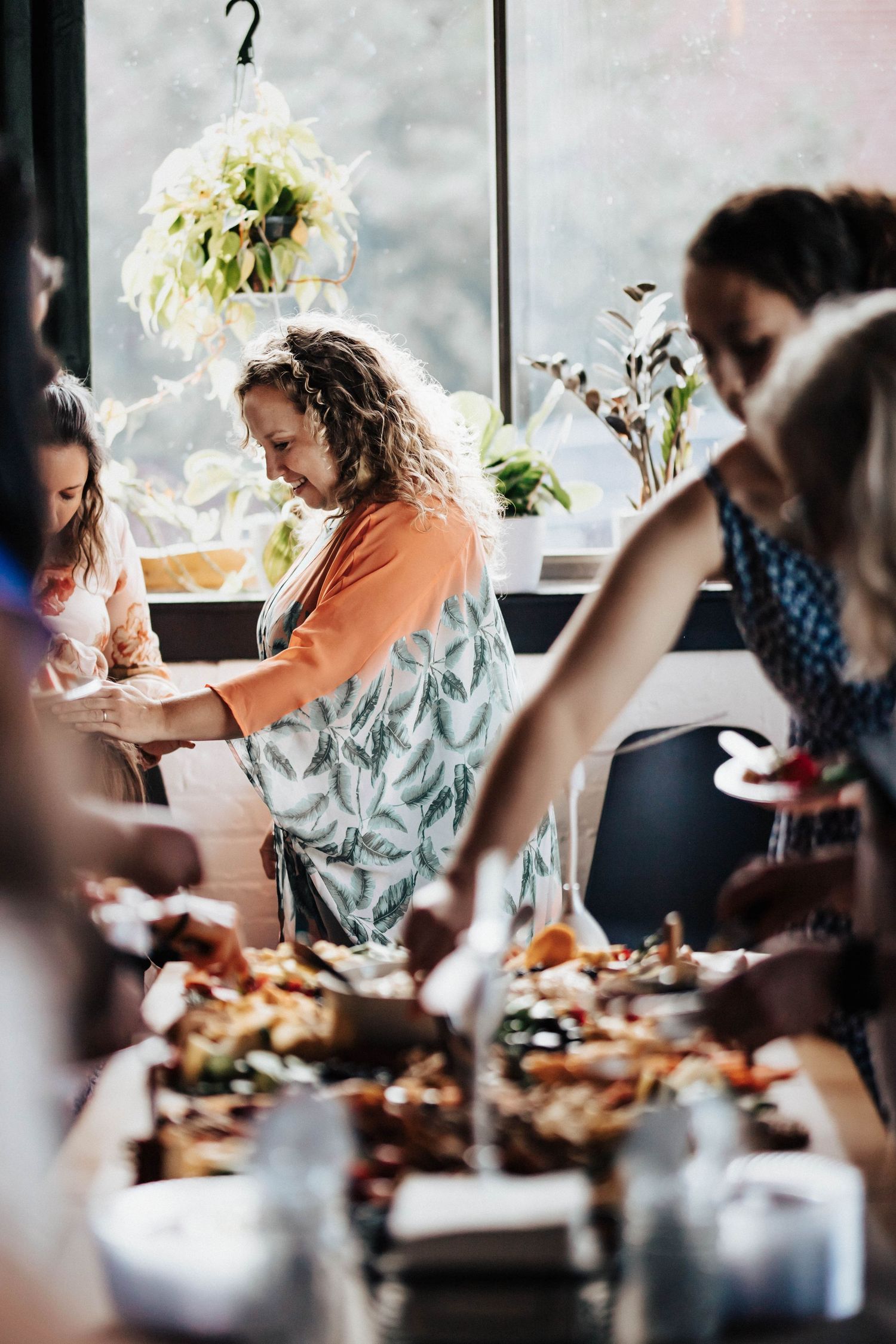 Woman in apron serves food at a buffet table during an indoor gathering event.