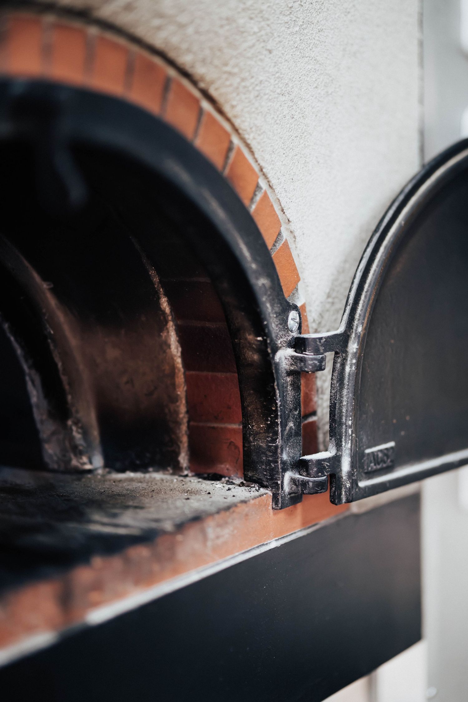 Interior view of a traditional brick wood-fired pizza oven with arched opening.