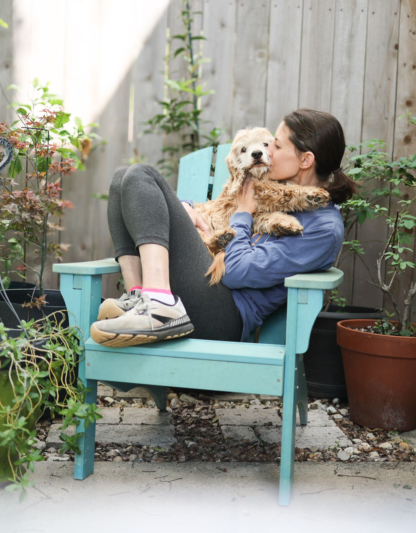 Woman snuggling with her dog on adirondack chair on patio