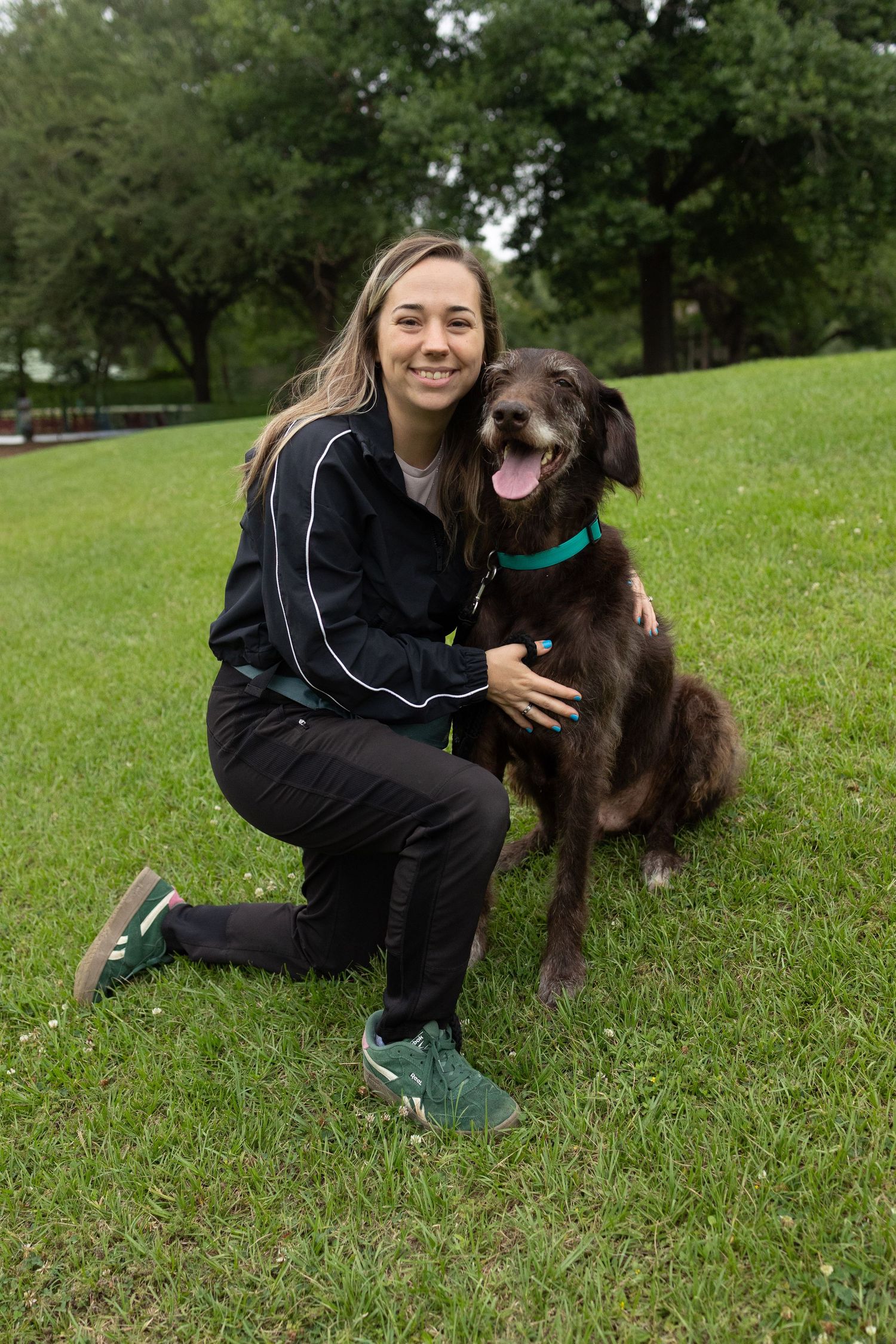 Pet parent kneeling next to her chocolate schnauzer mix.