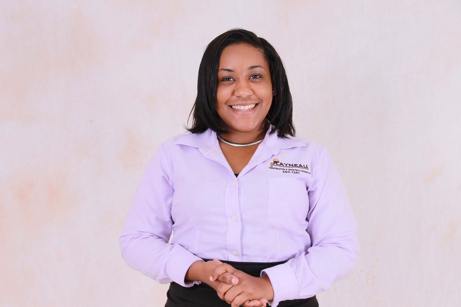 Professional woman in lavender button-up shirt smiling confidently against a neutral background.