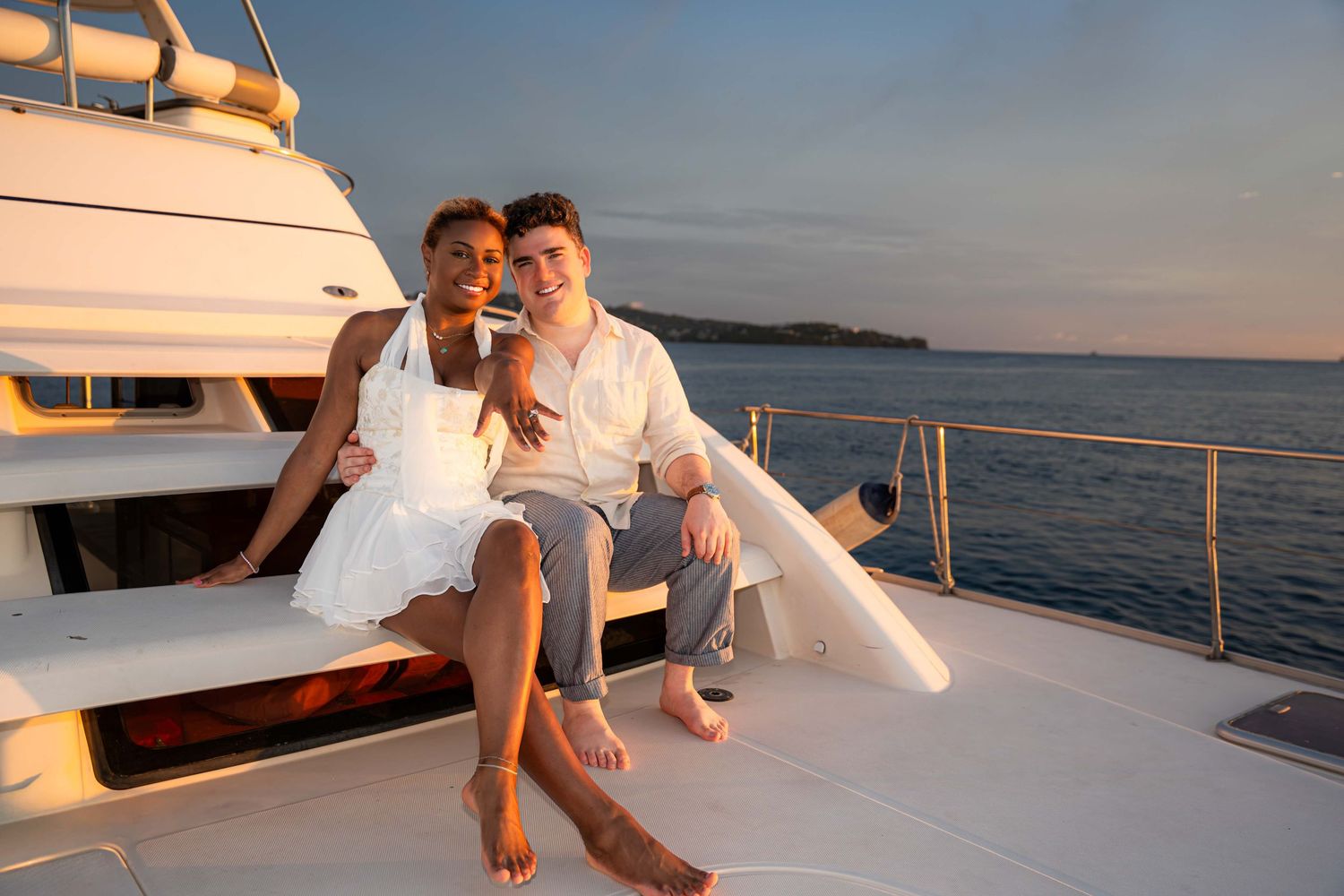 Couple relaxing together on a luxury yacht deck at sunset with calm ocean waters in the background.