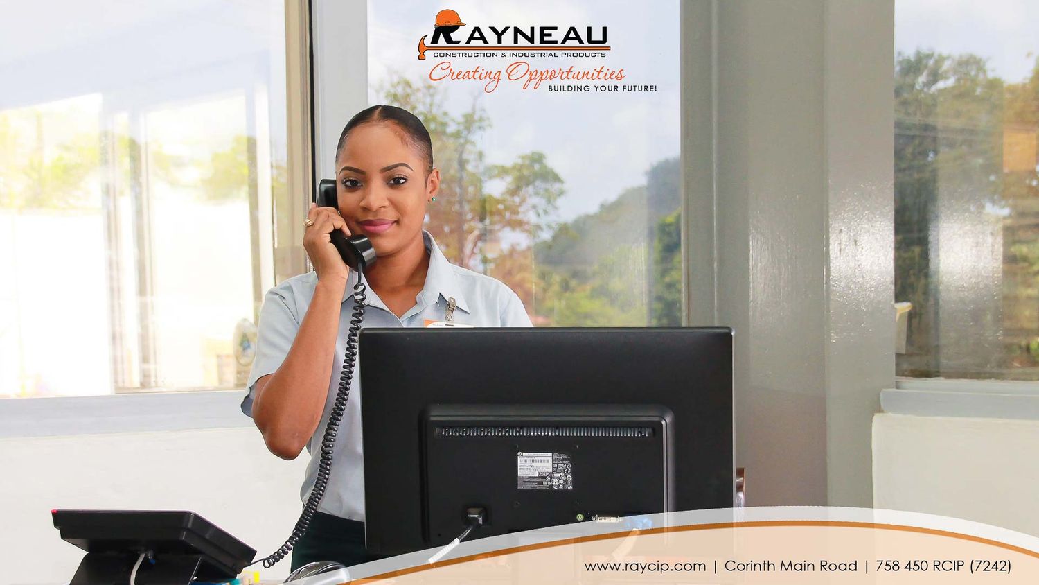 A professional receptionist answers a phone call at a modern front desk with a computer monitor at Rayneau office.