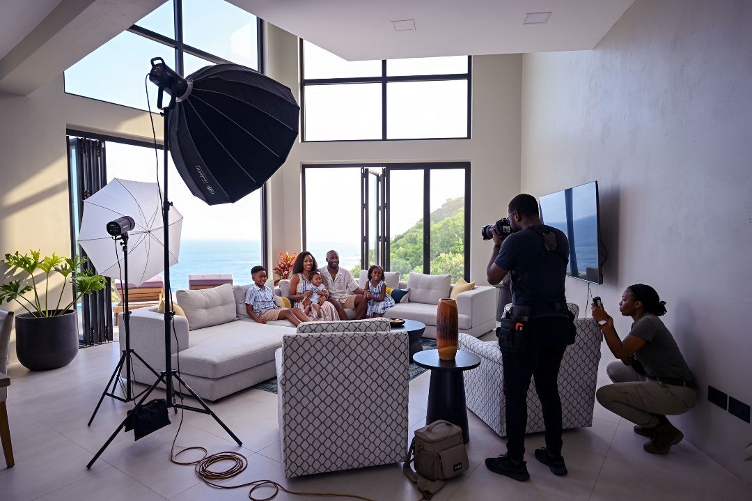 Photographers capturing a group portrait in a modern living room with ocean views and professional studio lighting equipment.