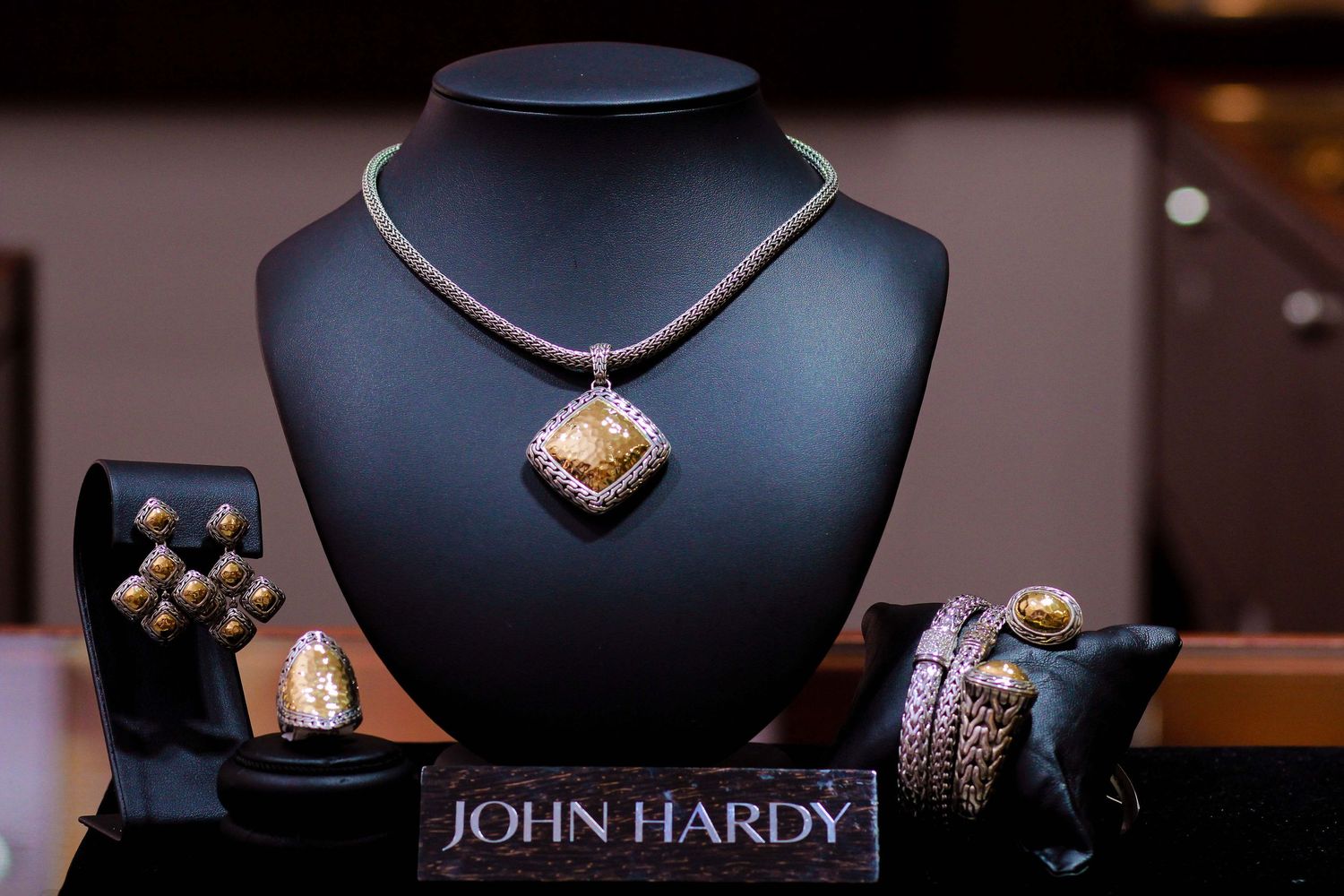 John Hardy luxury jewelry display featuring a diamond pendant necklace, earrings, ring, and bracelet on a black velvet bust.