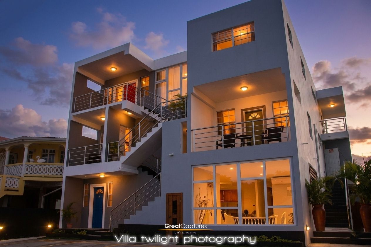 Modern multi-story villa photographed at twilight with warm interior lighting and elegant exterior staircases.