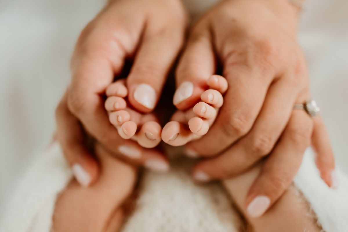Parents gently cradling their newborn baby's tiny feet in their hands, a tender moment of new parenthood.
