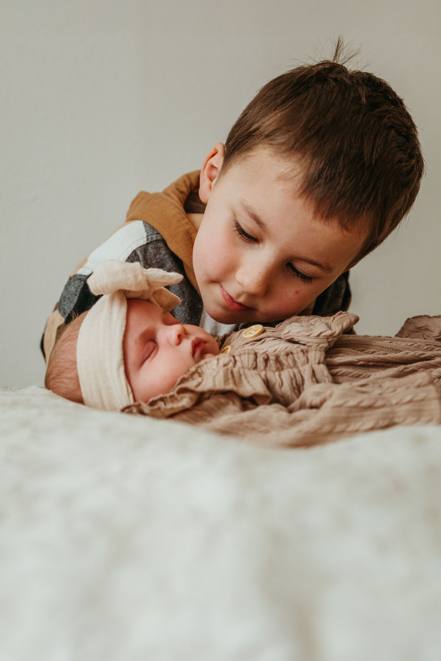 A child sleeps peacefully on a soft beige blanket in a series of intimate close-up photos.