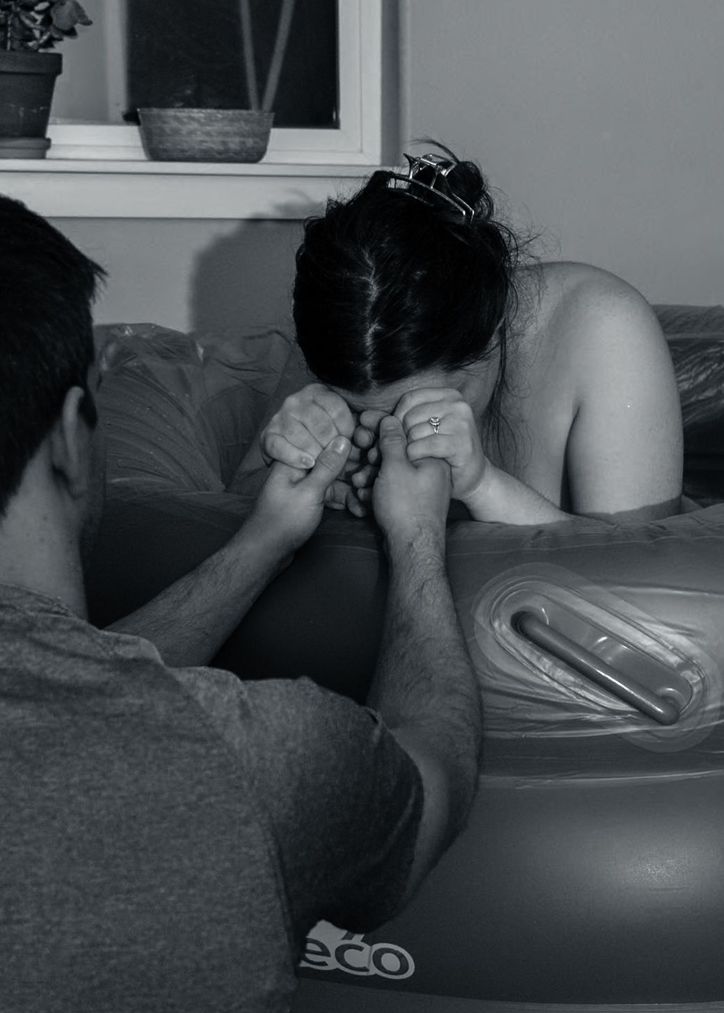 A black and white image showing hands being held during childbirth preparation.